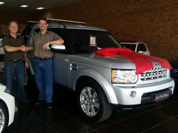Two men beside silver SUV with large red bow