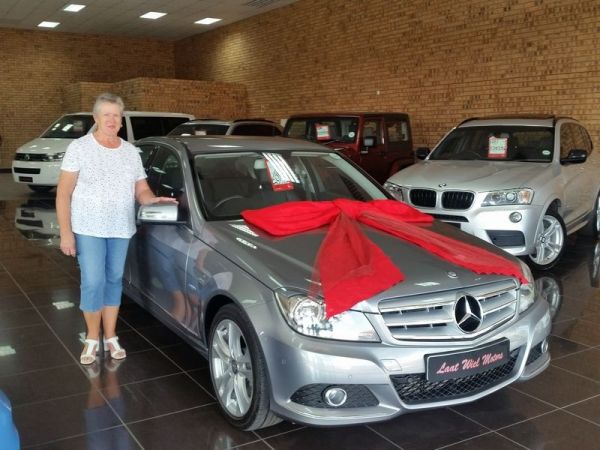 Woman stands beside Mercedes-Benz with large red gift bow