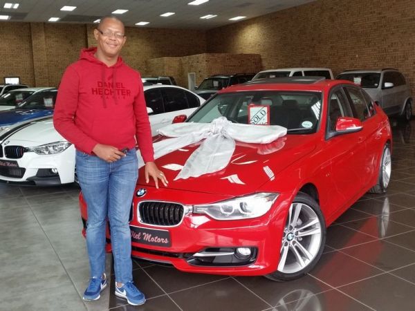 Man standing beside red BMW with large gift bow