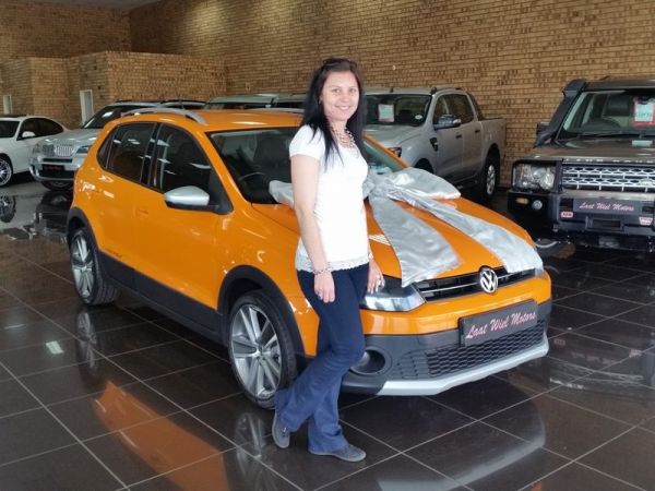 Woman standing beside orange Volkswagen with silver gift bow
