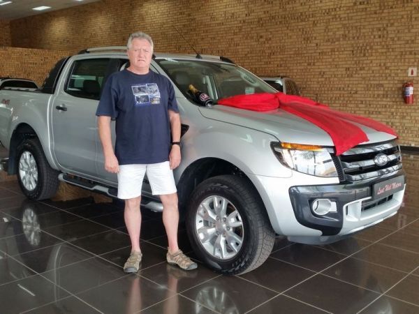 Man standing beside silver pickup truck with red bow
