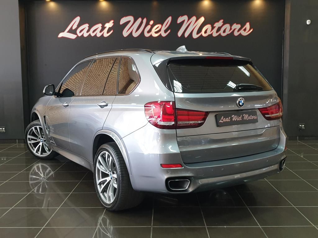 Silver BMW X5 SUV displayed in a dealership showroom