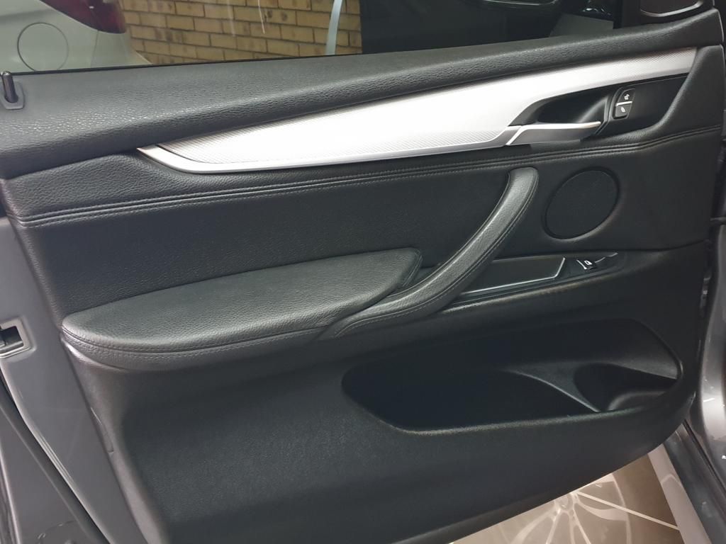 Black car interior door panel with silver trim and speaker