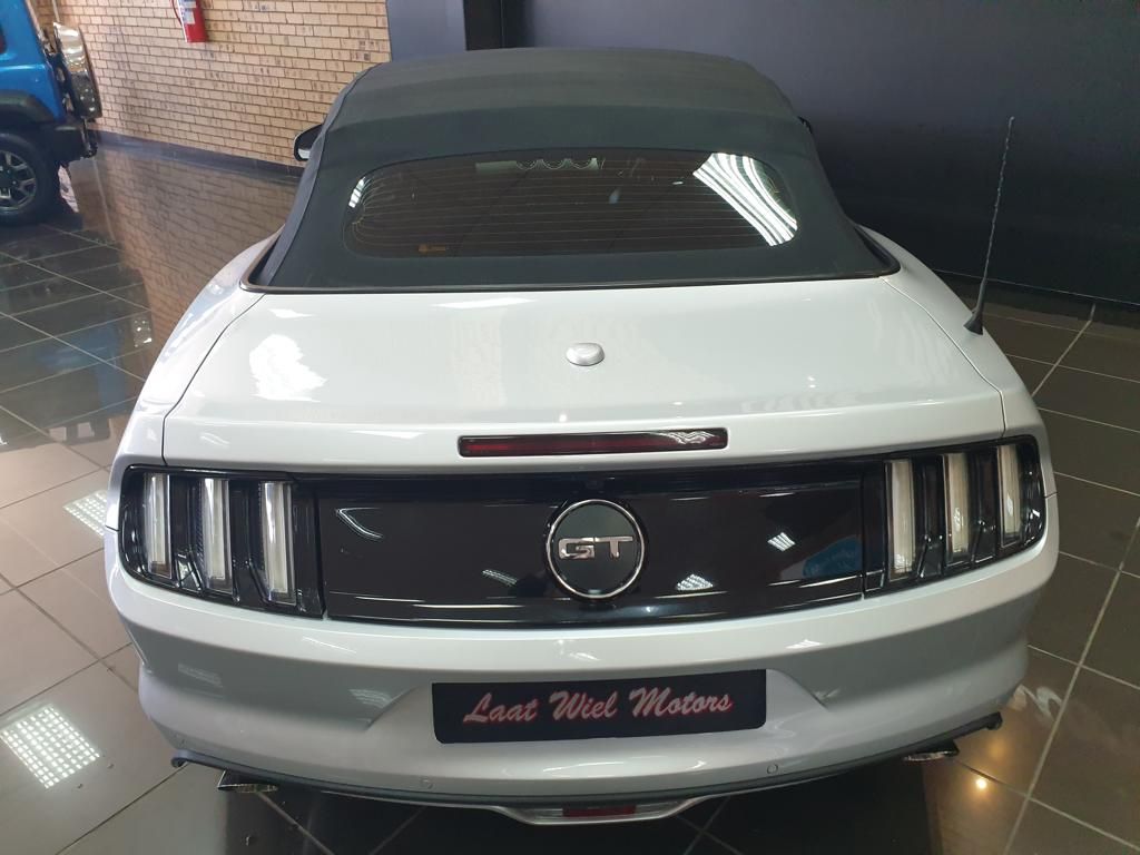 Rear view of a white Ford Mustang convertible in showroom