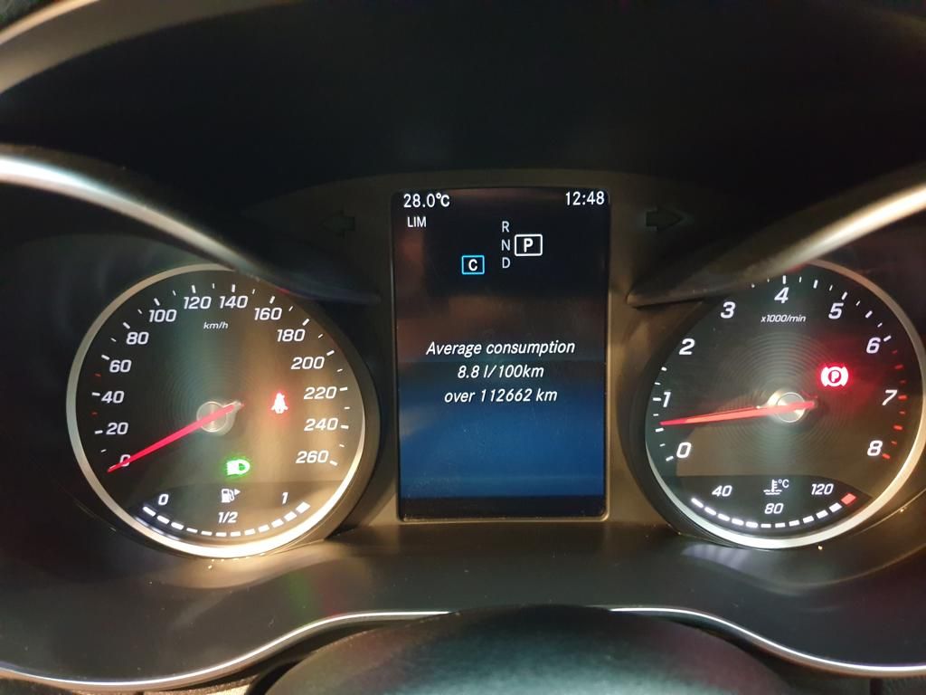 Car dashboard showing speedometer, tachometer, and average fuel consumption.