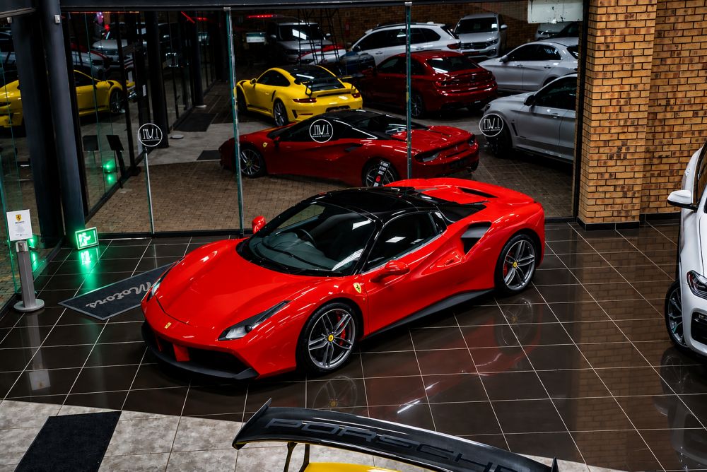 Red Ferrari sports car displayed in luxury dealership showroom